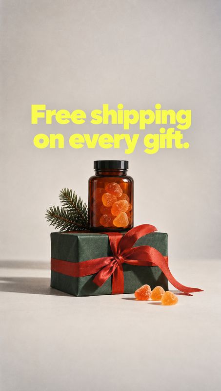 gummy supplement bottle personal care product photo: A jar of orange gummies sits atop a dark green gift wrapped with a red ribbon and evergreen sprig, beneath…