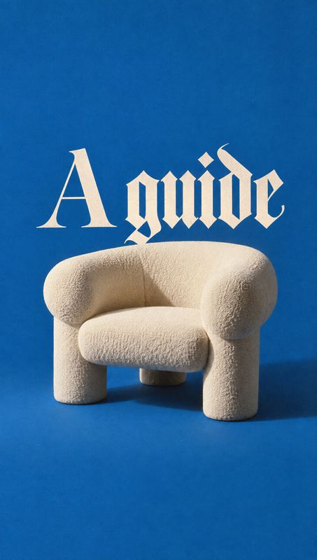 upholstered chair packshot product photo: A sculptural cream upholstered chair sits against a vivid blue studio backdrop, with large cream gothic lettering abo…