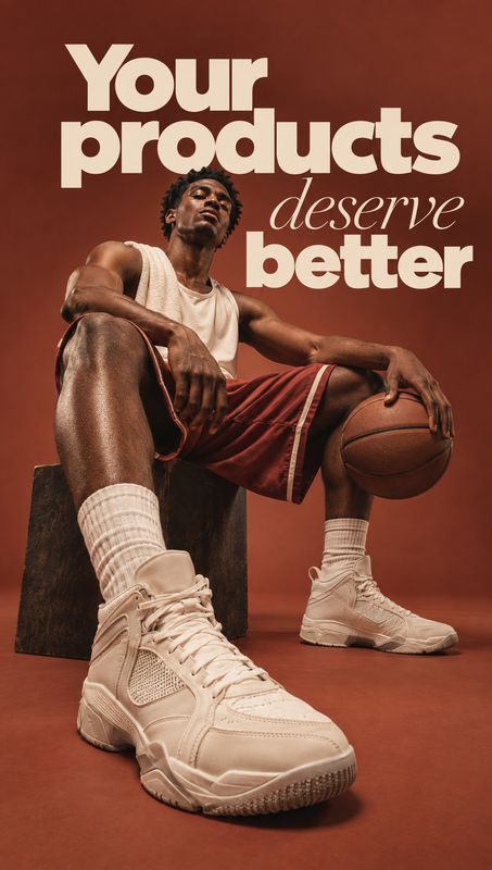 basketball sneakers fashion product photo: A seated basketball player wears oversized cream sneakers against a warm rust-colored studio backdrop, with bold cre…