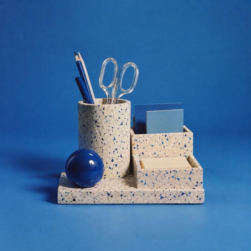 terrazzo desk organizer stationery product photo: A terrazzo desk organizer holding pencils, scissors, and notes sits with a glossy blue sphere against a vivid…