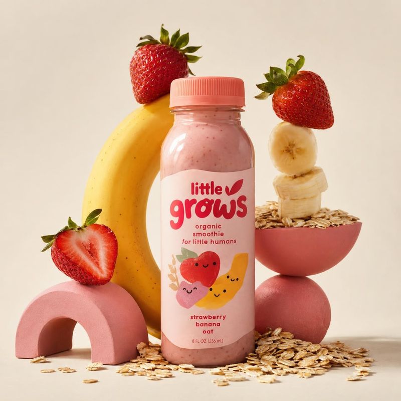 strawberry banana oat smoothie ingredients product photo: A pink strawberry-banana oat smoothie bottle stands among strawberries, banana, and scattered oats on…
