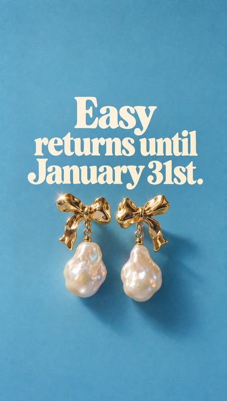 pearl bow earrings packshot product photo: Gold bow and baroque pearl earrings rest against a textured blue backdrop beneath large cream-colored return-policy…