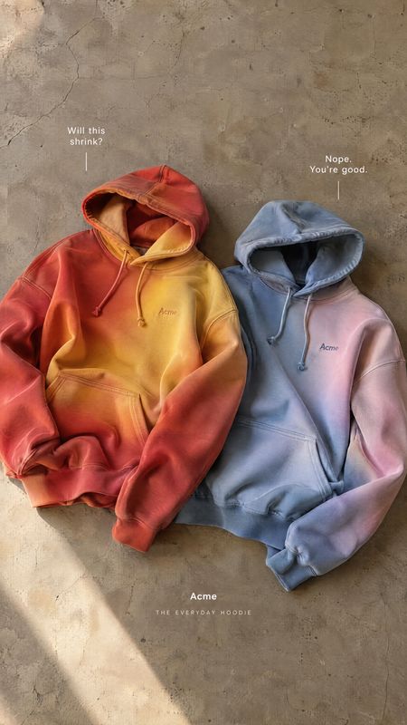 hoodies group lineup product photo: Two color-blocked hoodies are arranged on a textured concrete surface with small comparison callouts and soft angled light,…