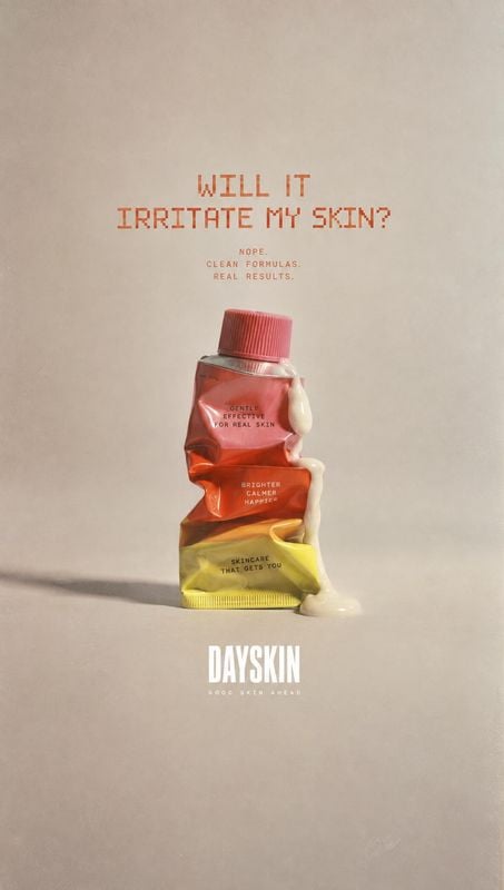 skincare tube packshot product photo: A crumpled red-and-yellow skincare tube with cream squeezed out sits against a warm beige studio backdrop, beneath bold r…
