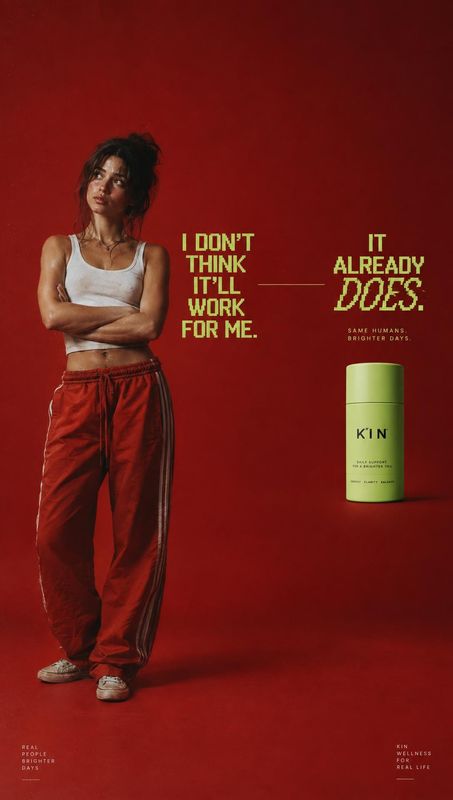 wellness supplement bottle personal care product photo: A woman in a white crop top and red track pants stands with folded arms against a vivid red studio back…