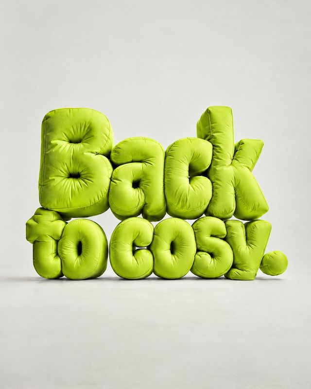Padded letter cushions close-up detail product photo: Bright lime-green, puffed cushions spell “Back to cozy!” against a pale studio backdrop, creating a playf…