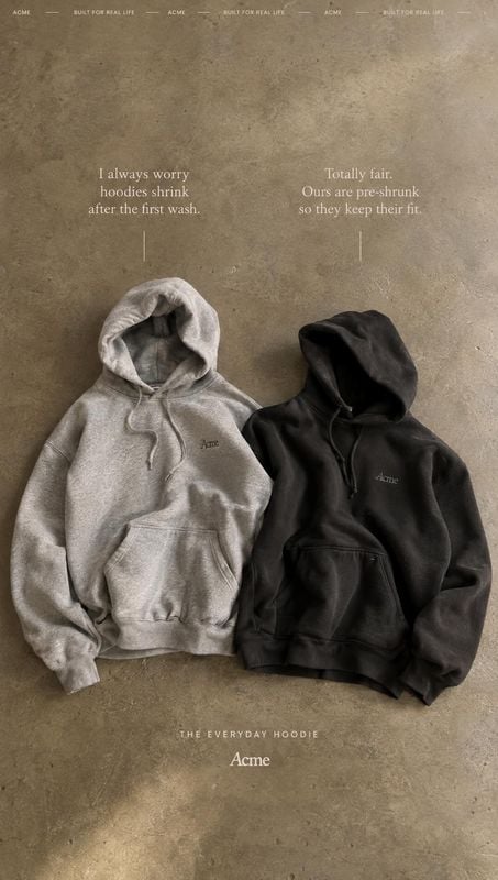 hoodies flat lay product photo: Two neutral-toned hoodies are arranged on a textured concrete surface beneath understated product copy, with soft, muted lighti…
