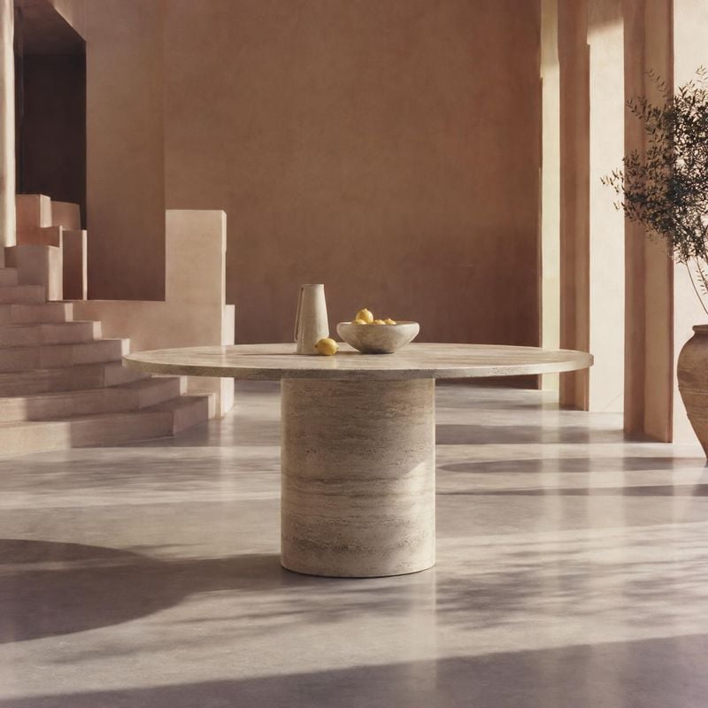 dining table interior space product photo: A sculptural stone dining table stands in a warm minimalist interior, styled with a bowl of lemons and softly lit by…