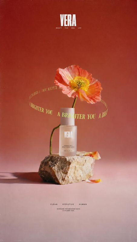 skincare bottle ingredients product photo: A pale skincare bottle rests on a rough stone beneath a vivid poppy, staged against a red-to-pink studio backdrop wi…