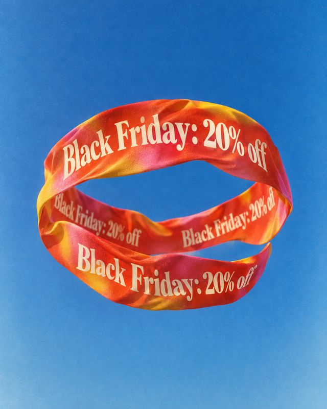floating product product photo: A glossy red-orange ribbon printed with “Black Friday: 20% off” floats against a vivid blue background, creating a bold, playfu…