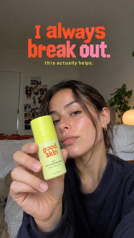 day balancing serum product in hand product photo: A woman holds a lime-green skincare bottle close to the camera in a softly lit bedroom, with bold red and pi…