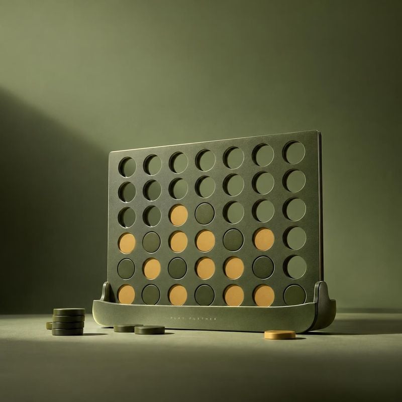 minimalist tabletop game board with playing discs toys product photo: A sculptural olive-green tabletop game board with mustard and dark discs is arranged on a…