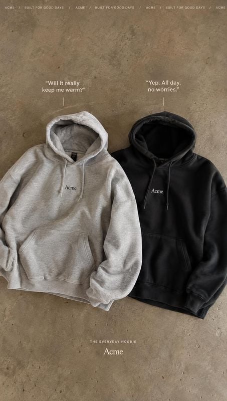 hoodies flat lay product photo: Two hoodies in gray and black lie side by side on a textured concrete surface, with restrained white copy and soft natural-look…