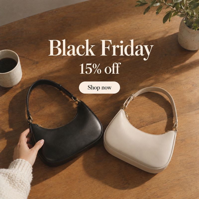handbags jewelry product photo: Two sleek handbags rest on a warm wooden tabletop beside a coffee cup and greenery, while a hand reaches toward the black bag b…