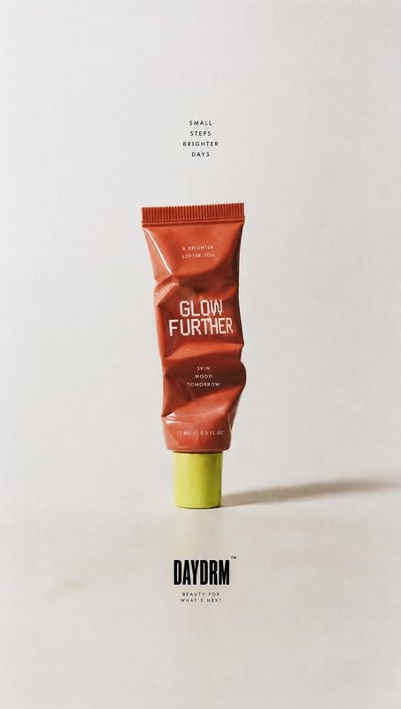 skincare tube packshot product photo: A copper-red skincare tube with a lime-green cap stands centered against a softly lit warm-white studio background, with…