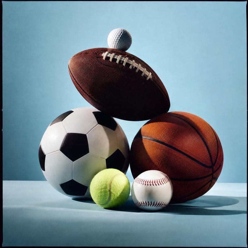assortment of sports balls sports product photo: A group of basketball, soccer, football, baseball, tennis and golf balls is arranged against a pale blue studi…