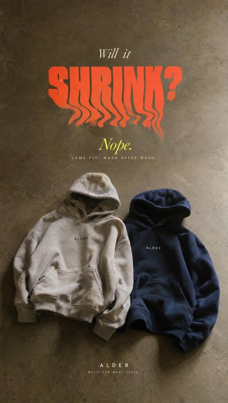 hoodies group lineup product photo: Two neutral-toned hoodies lie on a textured concrete surface beneath bold orange and cream typography, creating a moody app…