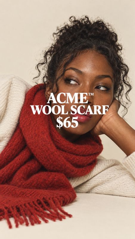 wool scarf on-body detail product photo: A woman in a cream knit sweater models a chunky red wool scarf against a warm beige studio backdrop, with bold white p…