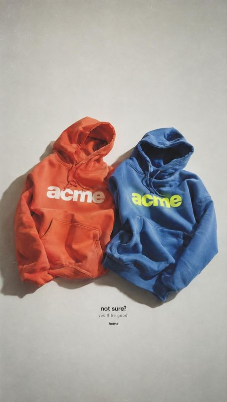 hoodies flat lay product photo: Two brightly colored hoodies lie side by side on a pale gray surface, with soft directional shadows and a small caption below c…