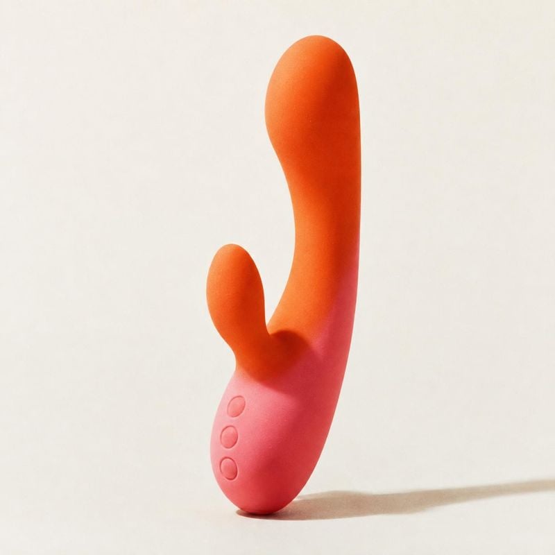 vibrating personal massager personal care product photo: A sculptural coral-pink personal massager stands alone against a warm off-white studio background, wit…