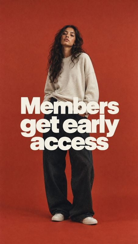 casual outfit black friday product photo: A model in a relaxed cream sweatshirt, dark wide-leg trousers, and sneakers poses against a warm red studio backdrop…