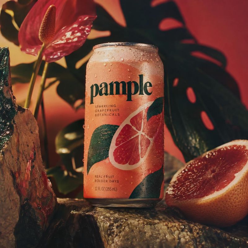 sparkling grapefruit drink ingredients product photo: A chilled can of sparkling grapefruit drink sits among citrus and tropical foliage, with warm dramatic li…