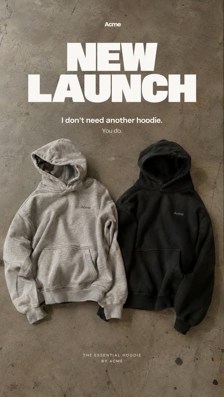 hoodies flat lay product photo: Two neutral-toned hoodies are arranged on a textured concrete surface beneath bold white launch typography, creating a minimal…