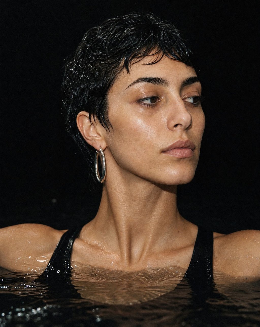 Woman emerging from dark water under hard flash lighting showing precise skin tone and tonal accuracy in high-contrast photography