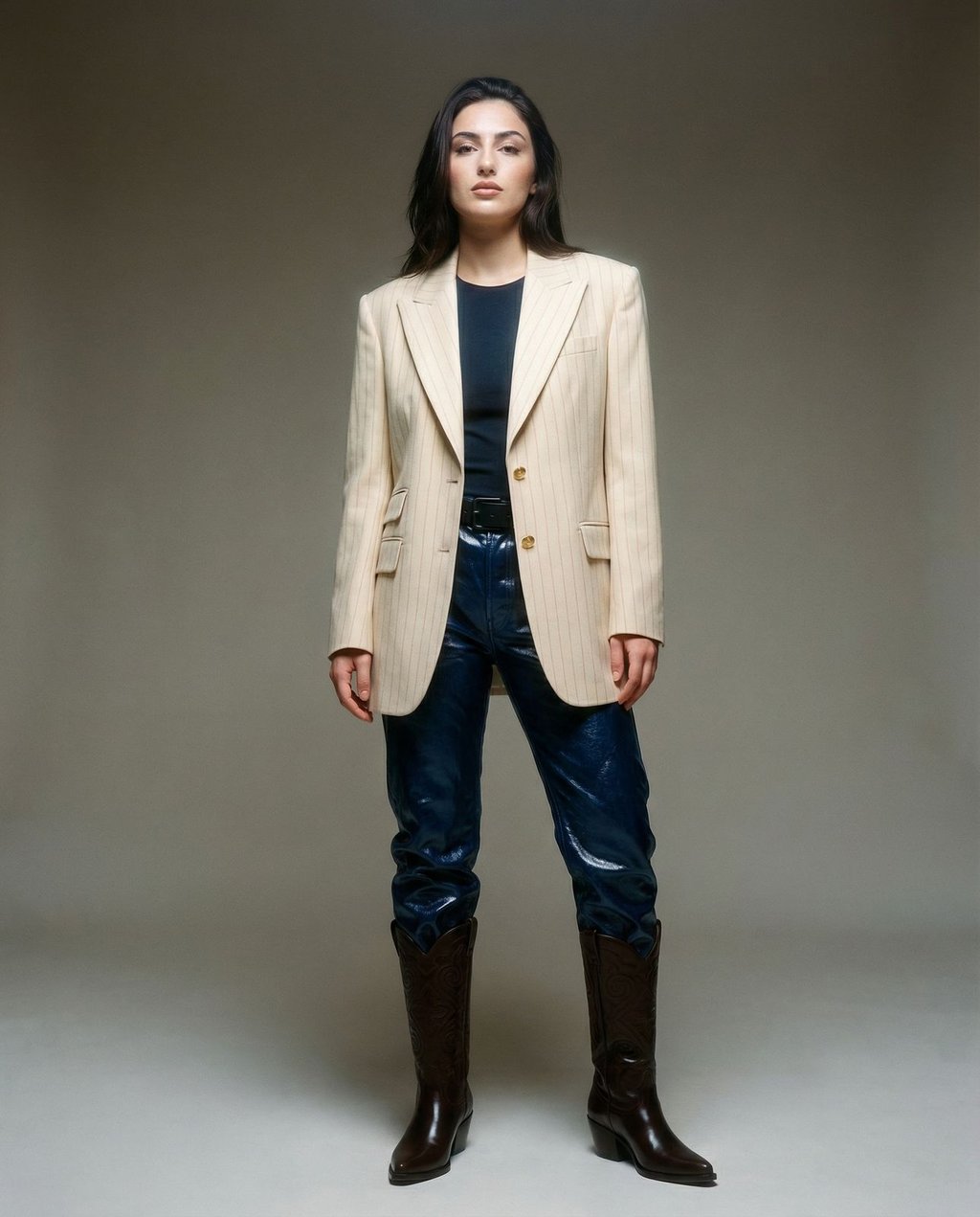 Full-body fashion portrait of a model in a cream pinstripe blazer against a minimalist grey studio backdrop, demonstrating consistent studio lighting and composition