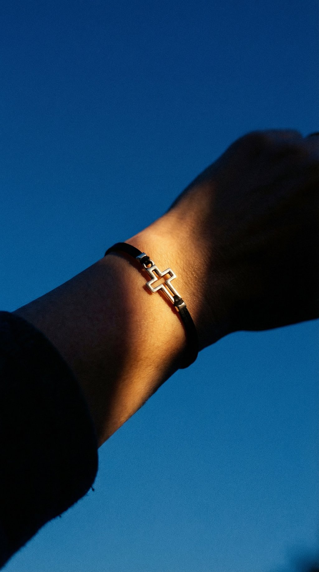 AI product shot of Women bracelet with silver outline cross charm, black cord