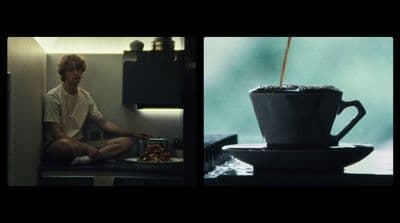 a man sitting on a counter next to a cup of coffee