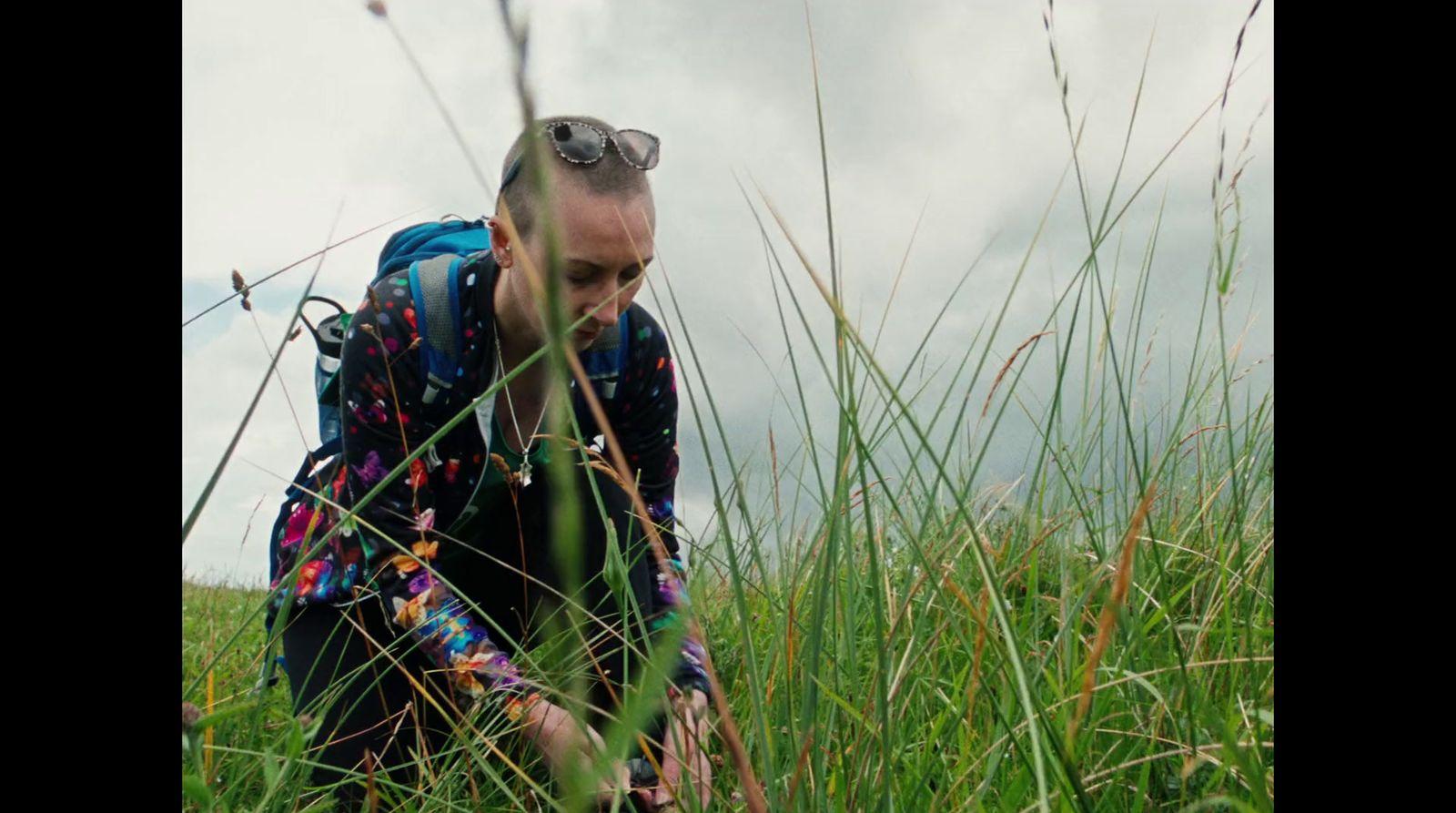 a man kneeling in a field of tall grass