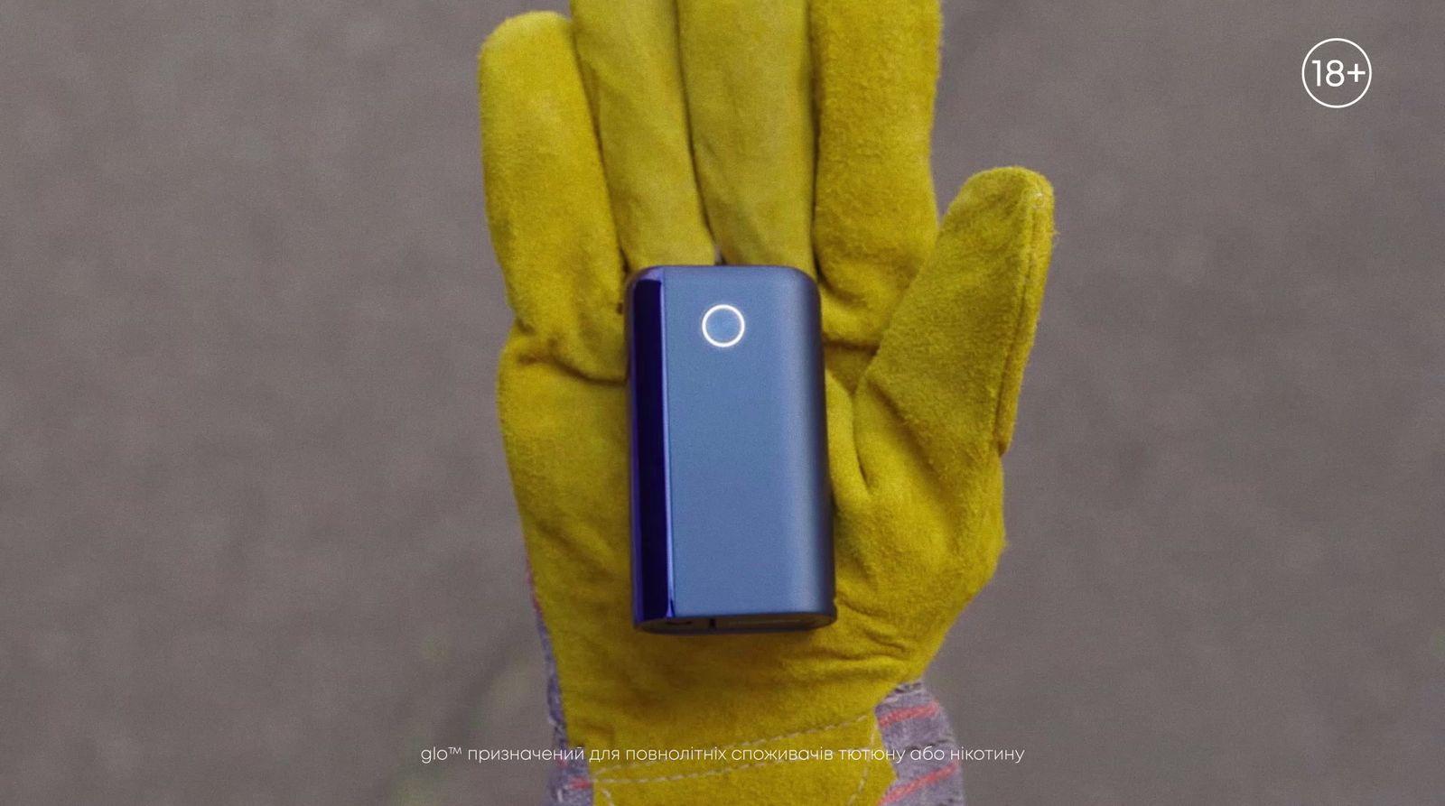a person wearing a yellow glove holding a blue device