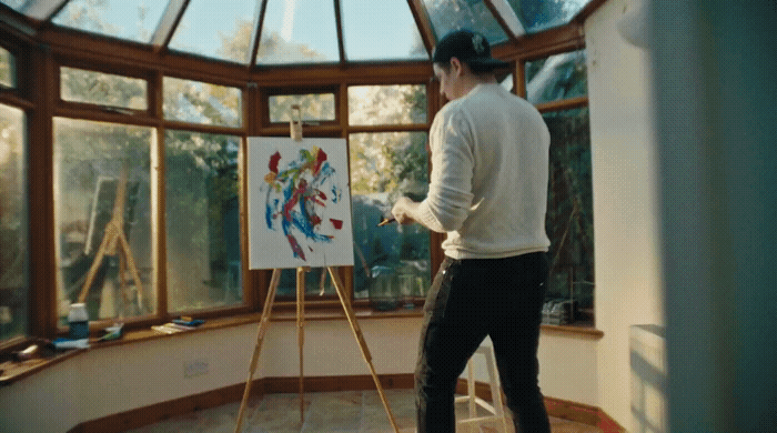 a man standing in front of a painting on a easel