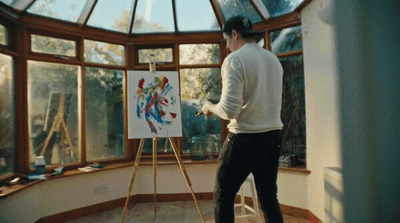 a man standing in front of a painting on a easel