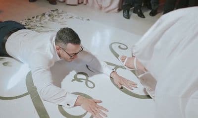 a man in a white suit and tie laying on the floor