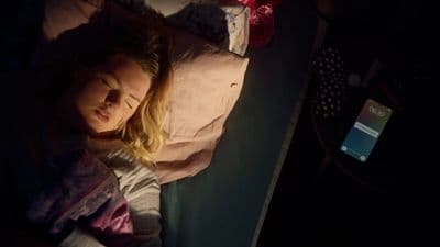 a woman laying in a bed with a cell phone