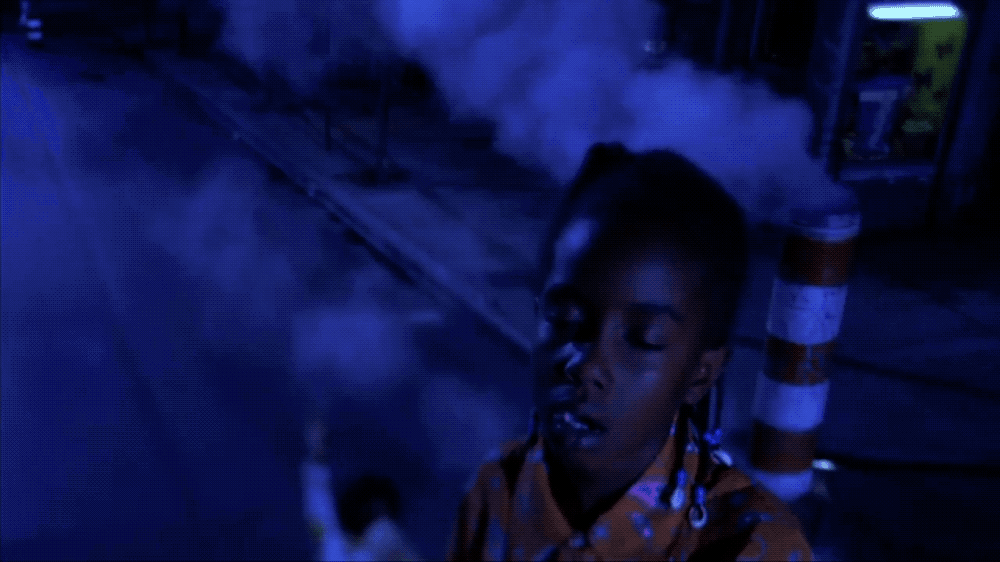 a young boy standing in front of a building with smoke coming out of it