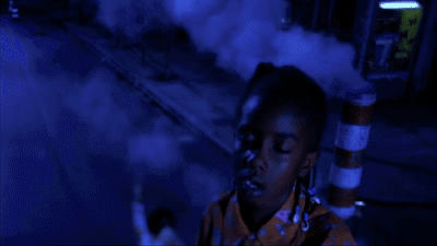 a young boy standing in front of a building with smoke coming out of it
