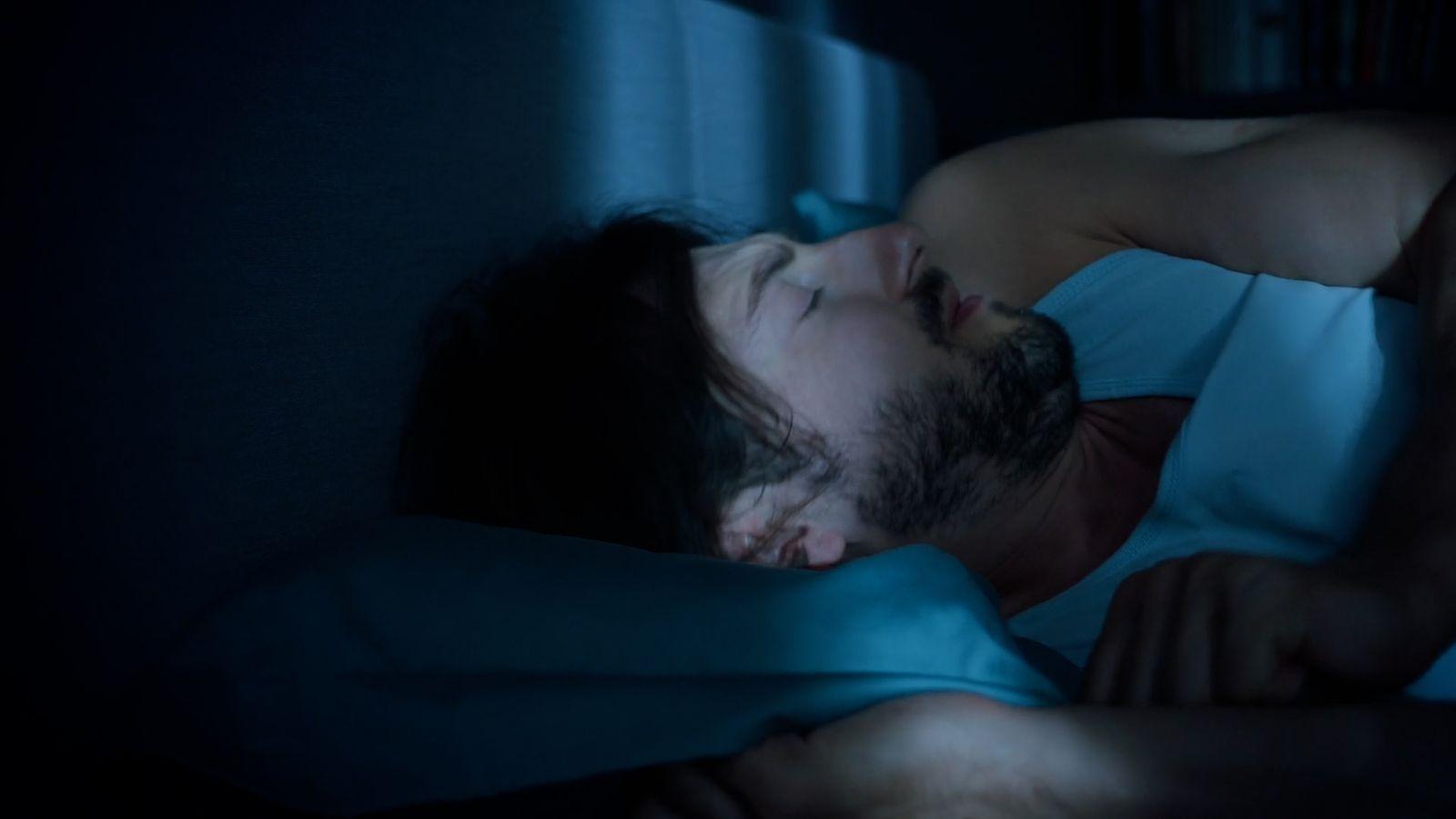 a man sleeping in bed at night with his eyes closed