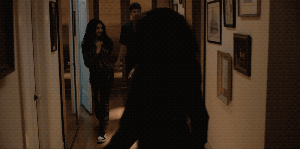 a woman walking down a hallway next to a man