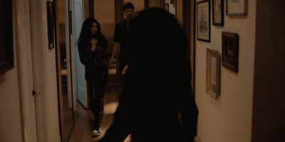 a woman walking down a hallway next to a man