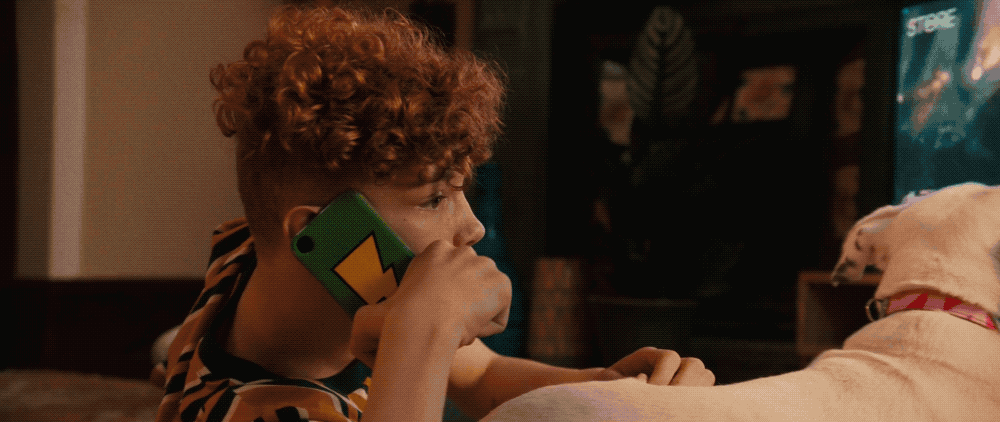 a child talking on a cell phone next to a dog