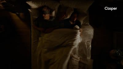 a couple of people laying in a bed under a blanket