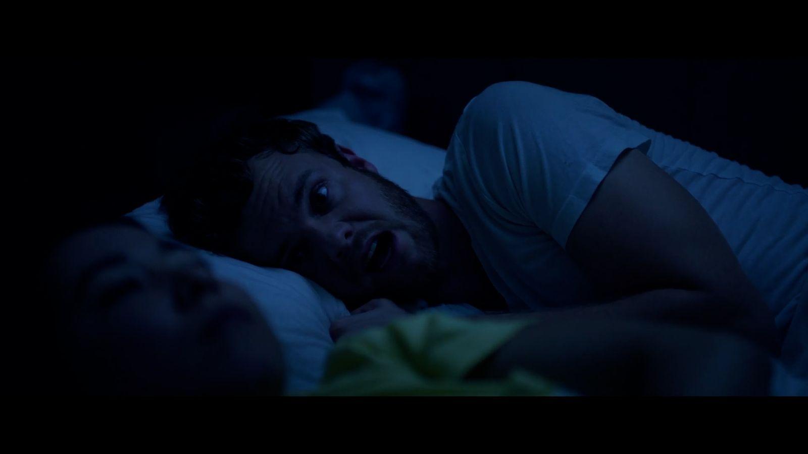 a man laying in bed with his mouth open