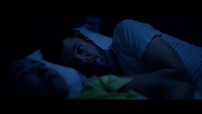 a man laying in bed in the dark