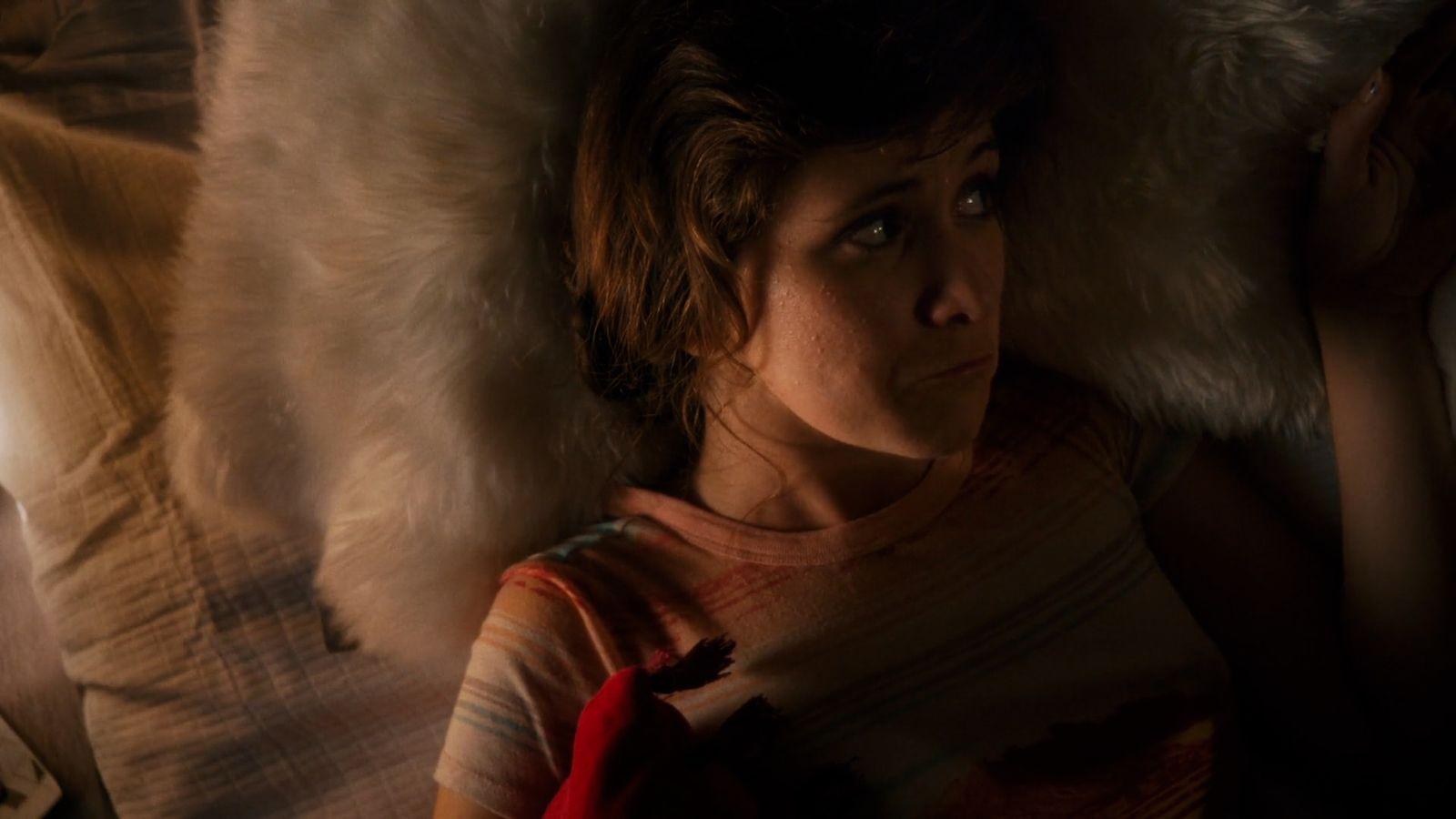 a woman laying on top of a bed under a blanket