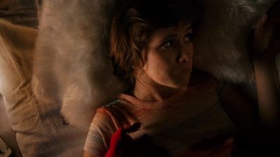 a woman laying on top of a bed under a blanket