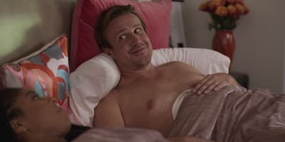a shirtless man laying in bed with a woman