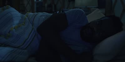 a man sleeping on a bed in a dark room